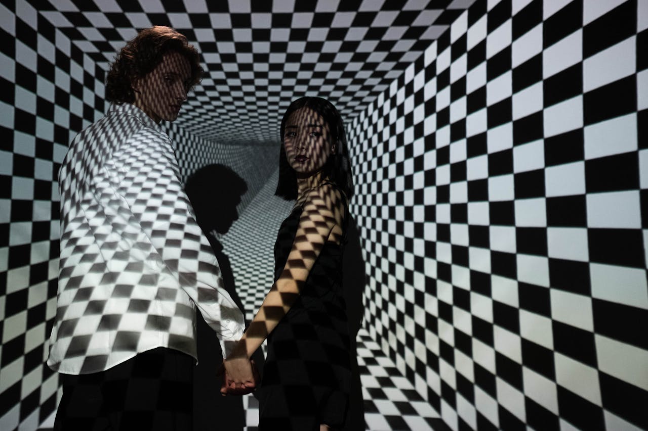 A man and woman stand in a checkered tunnel, creating a dramatic optical illusion.